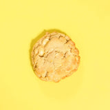 Lemon Meringue New York Cookie with white chocolate chunks and lemon zest on a bright yellow background by Crumbs & Doilies